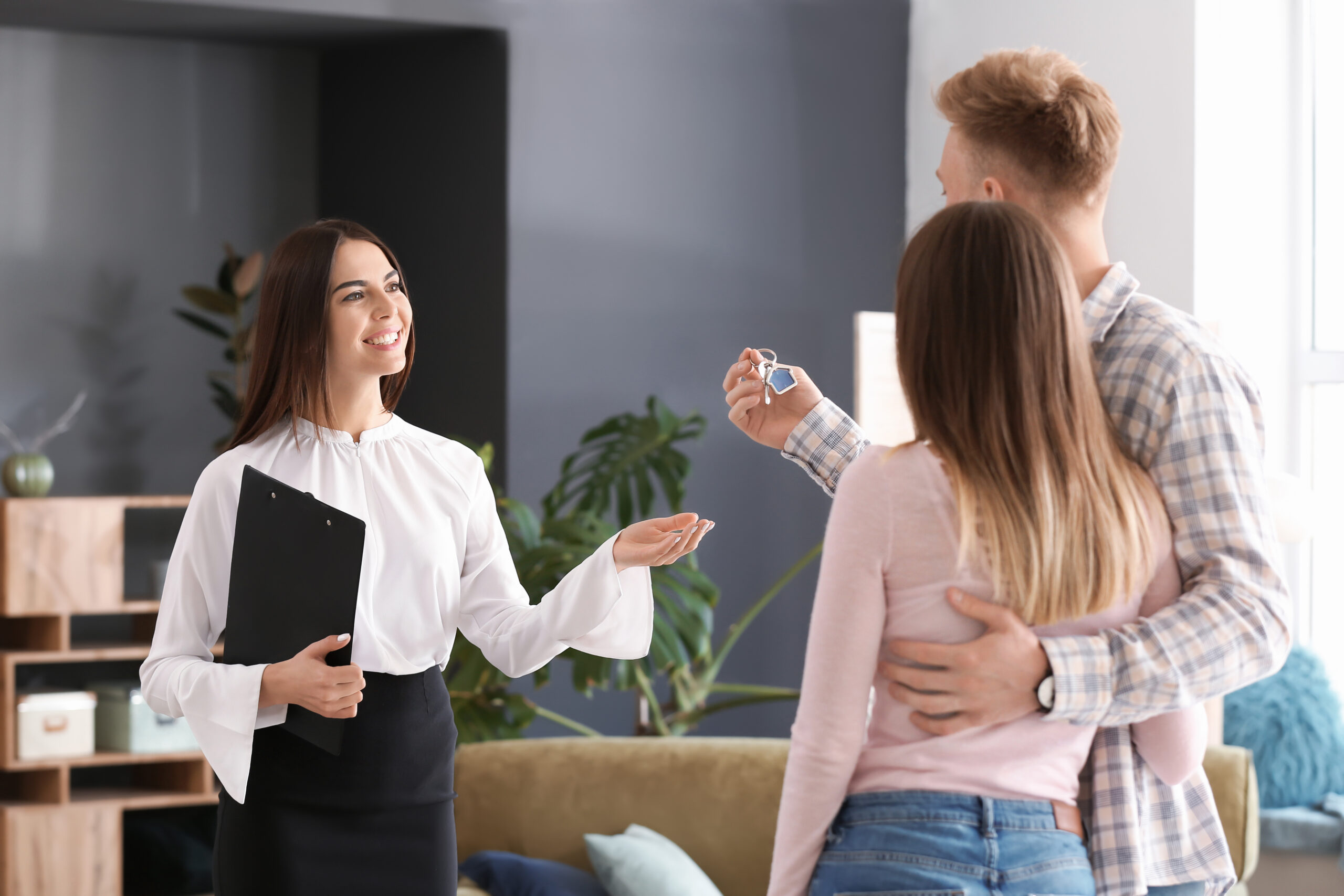 Real estate agent giving a key from new house to young couple